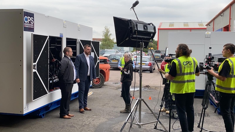 Daniel Arnett being filmed by Perkins in front of a generator at CPS Generators